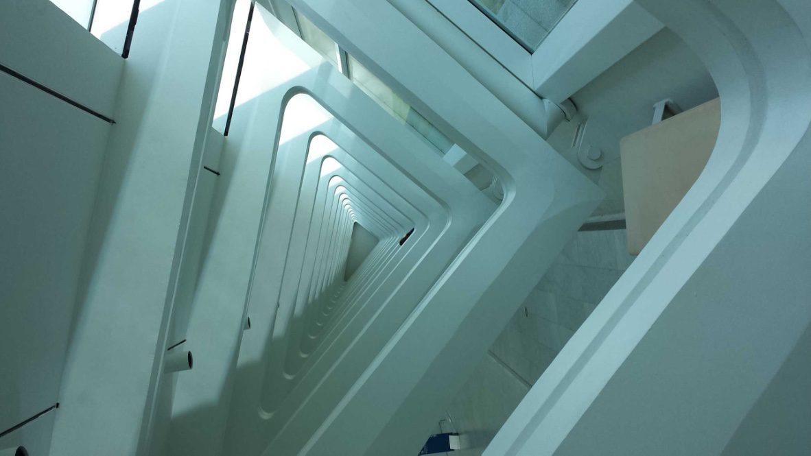 A spiraling architectural design featuring curved white walls and large windows, illustrating a modern, minimalist interior space.