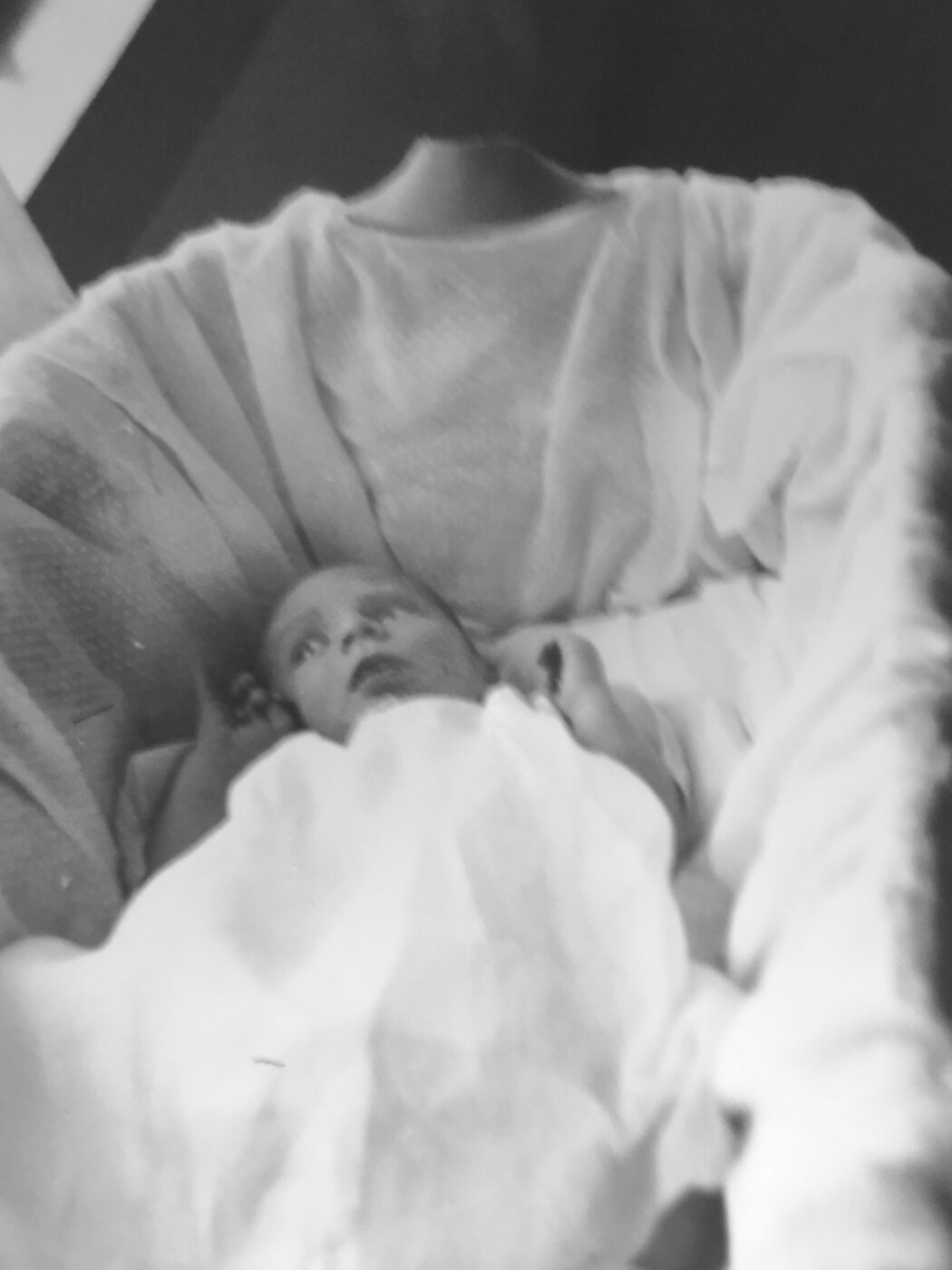 A newborn baby wrapped in a light blanket, lying in a bassinet. The image evokes feelings of tenderness and early childhood.