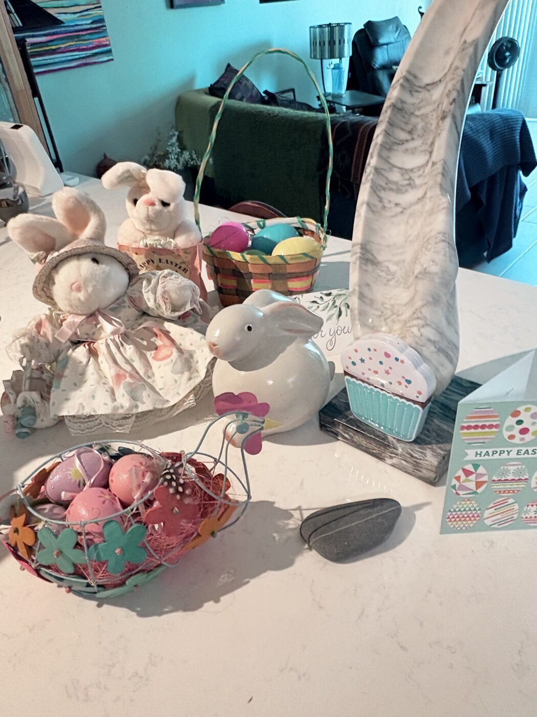 Easter-themed decorations featuring plush bunnies, colorful eggs in baskets, and a card wishing "Happy Easter" on a table setting.